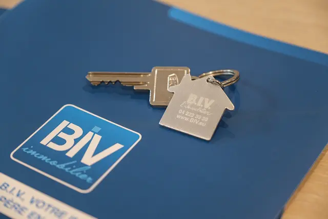 Porte-clés en forme de maison gravé B.I.V. immobilier, posé sur un dossier de vente de l'agence