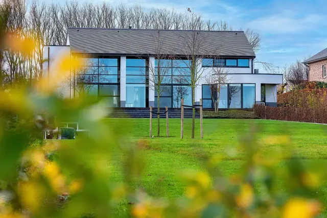 Moderne villa met grote raampartijen en groene tuin
