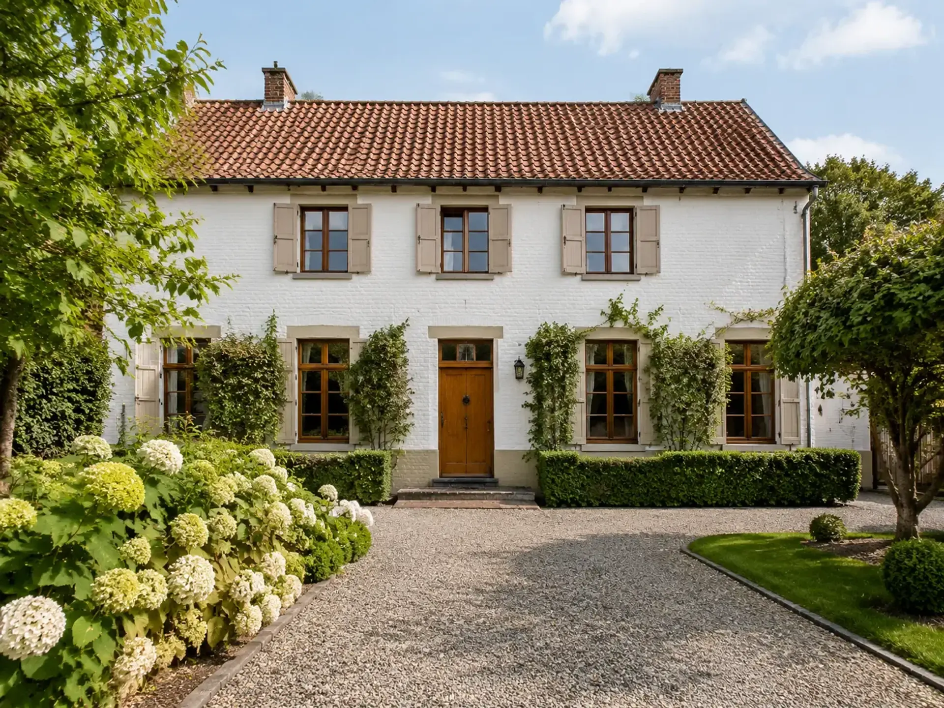 Witte landelijke woning met voortuin en blauwe lucht