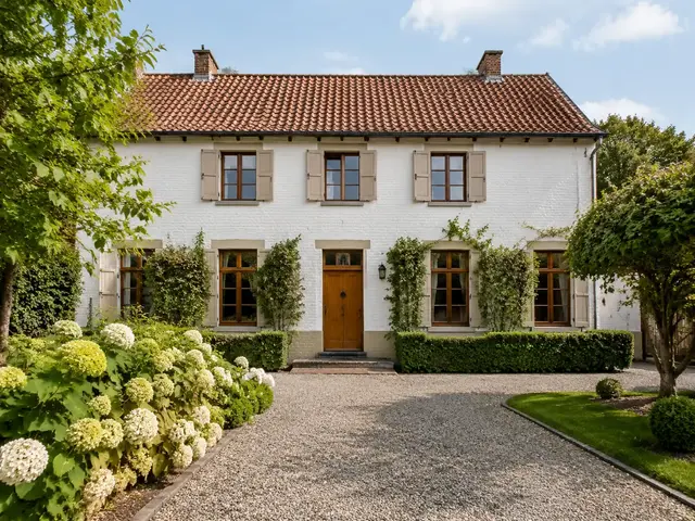 Witte landelijke woning met voortuin en blauwe lucht